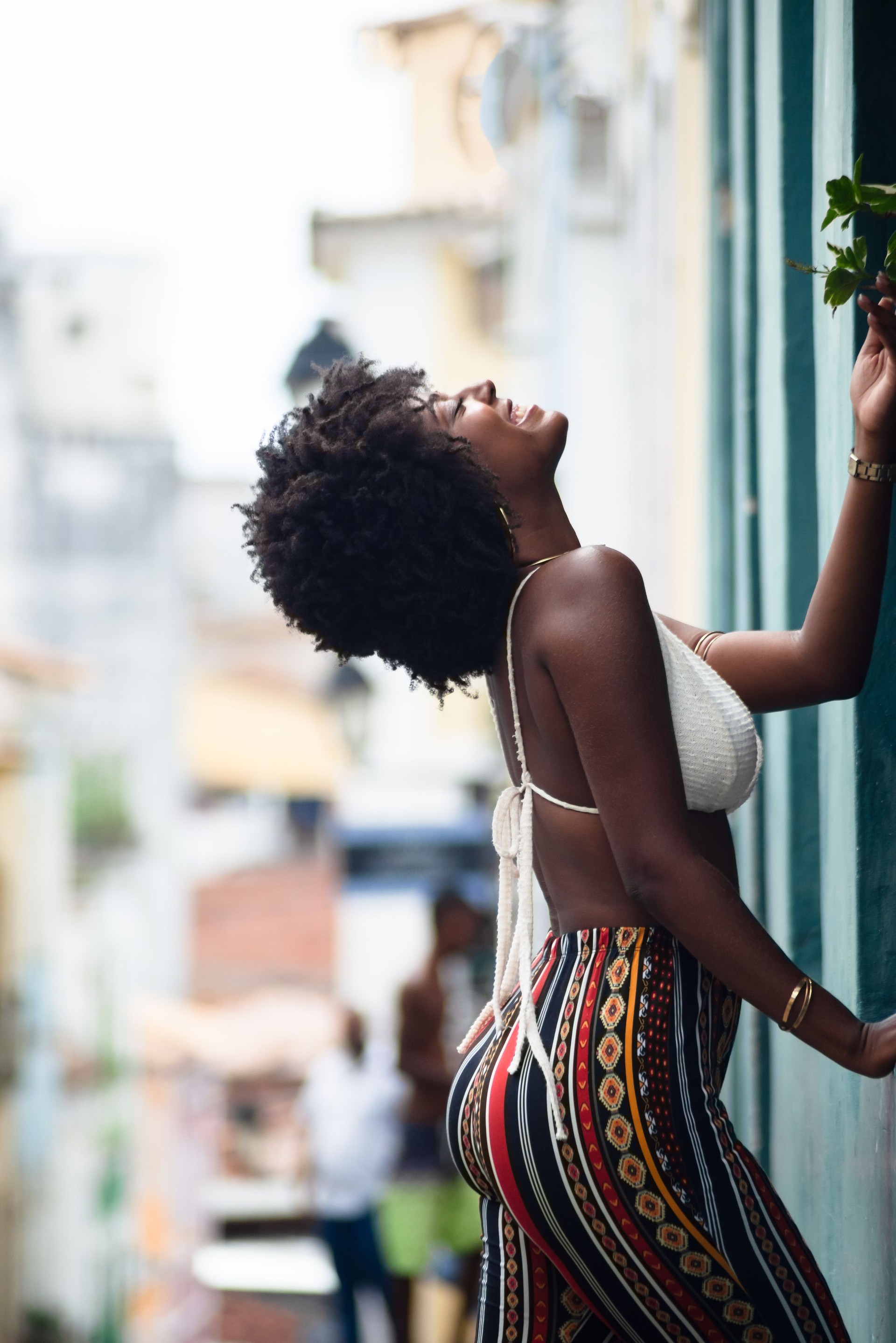 Beautiful, very smiling and happy woman leaning against a wall of an old house. Empowered and electrified person.